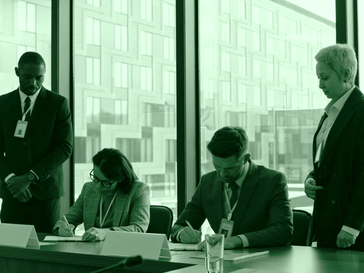 Two people signing their completed agreement